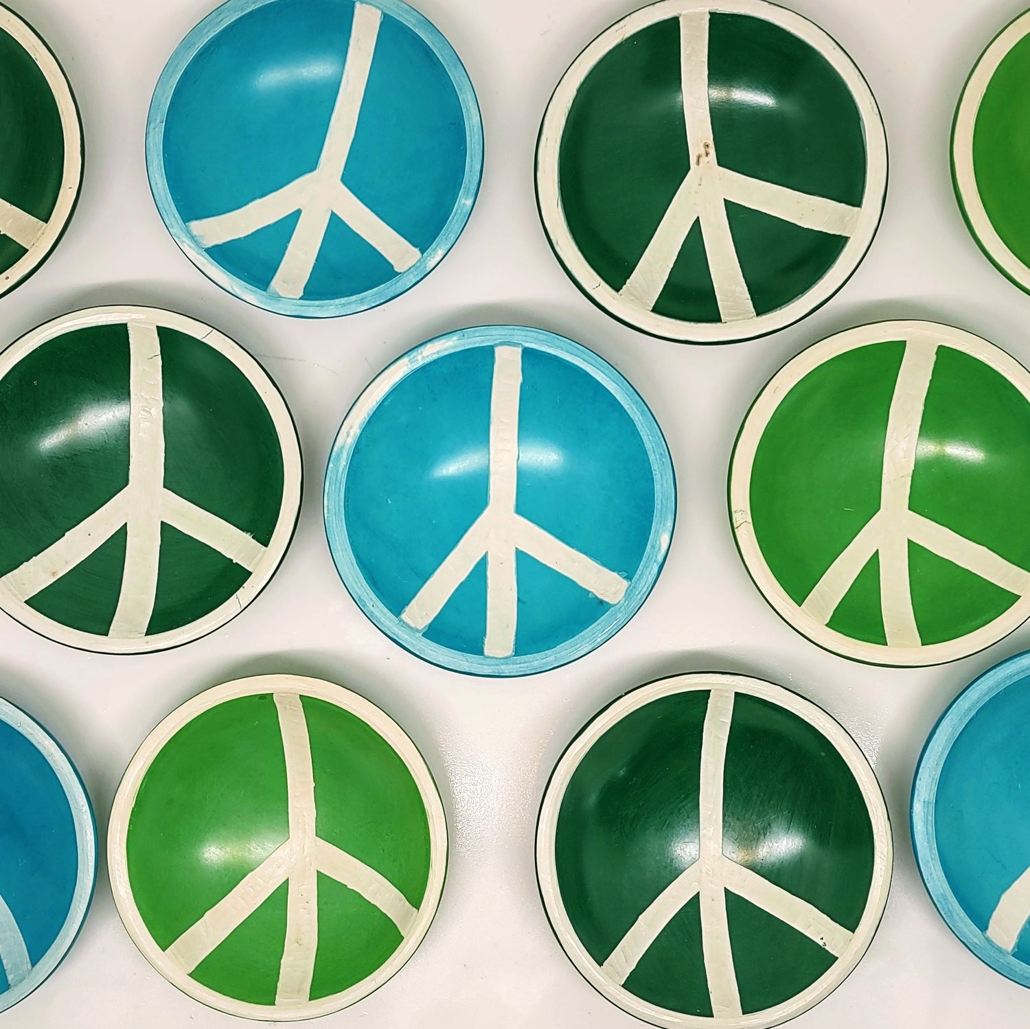 various green and blue peace sign trinket trays laid out on a white background