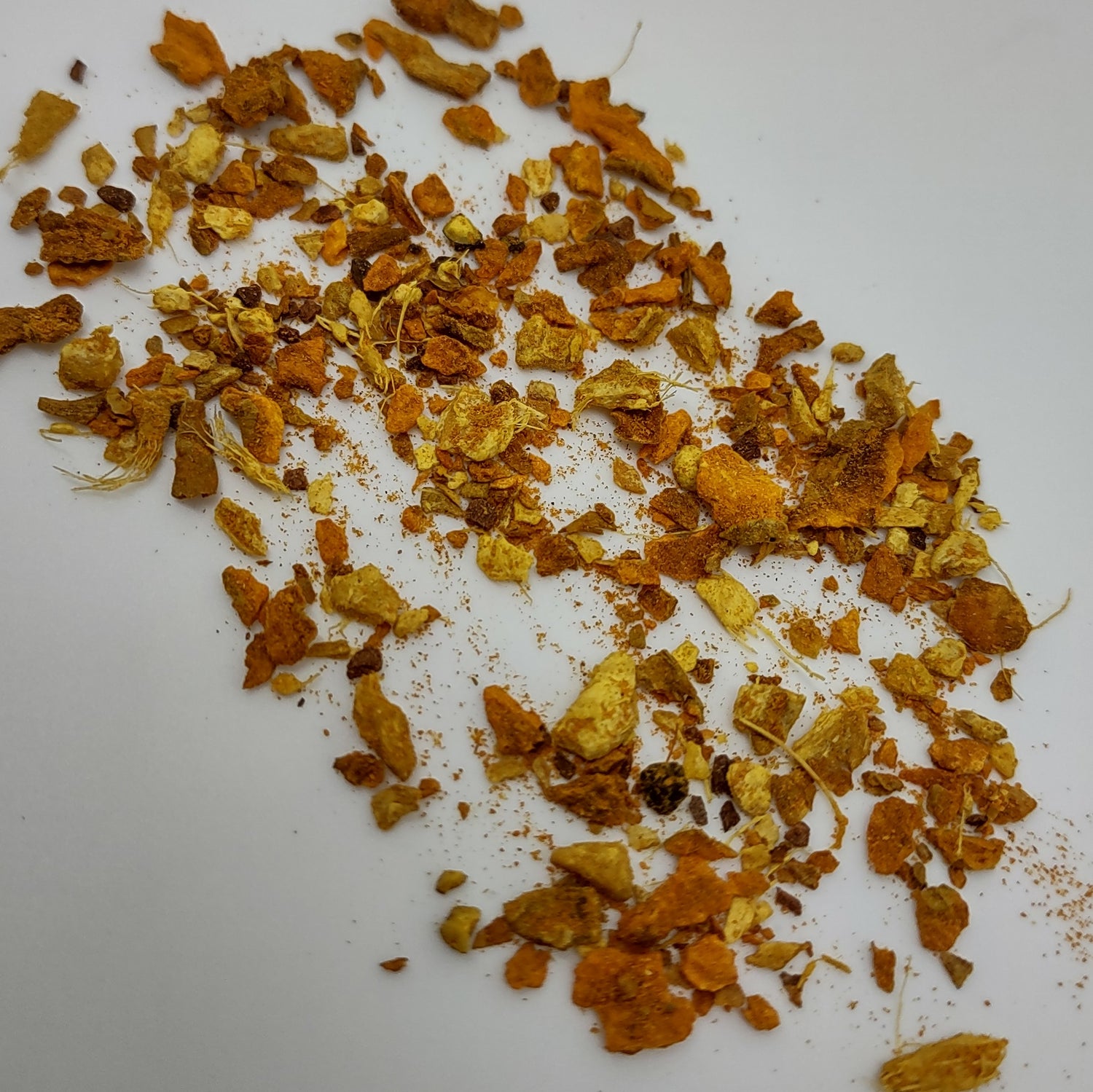 a handful of turmeric ginger tea tossed onto a white background