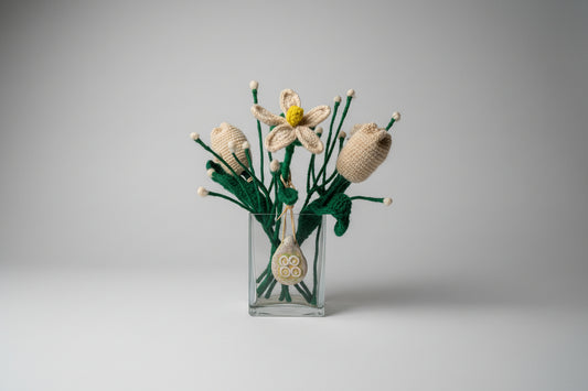 Knitted flowers in a clear glass bottle on a white surface